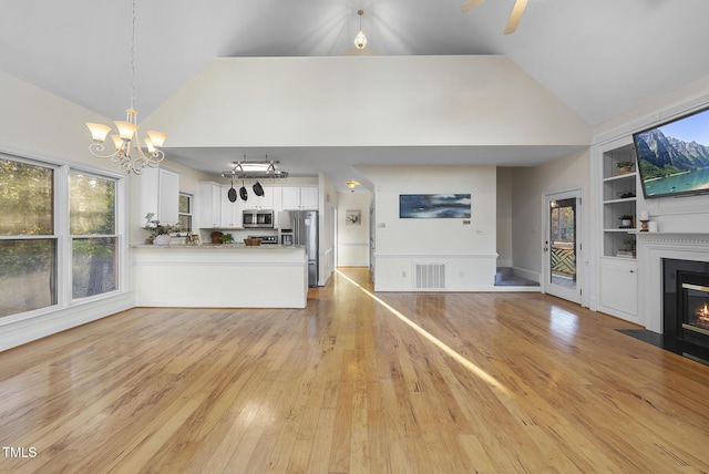50 Tyler Ct, Henderson, NC 27537 - unfurnished living room with a fireplace with flush hearth, a chandelier, built in features, high vaulted ceiling, and light wood-style floors