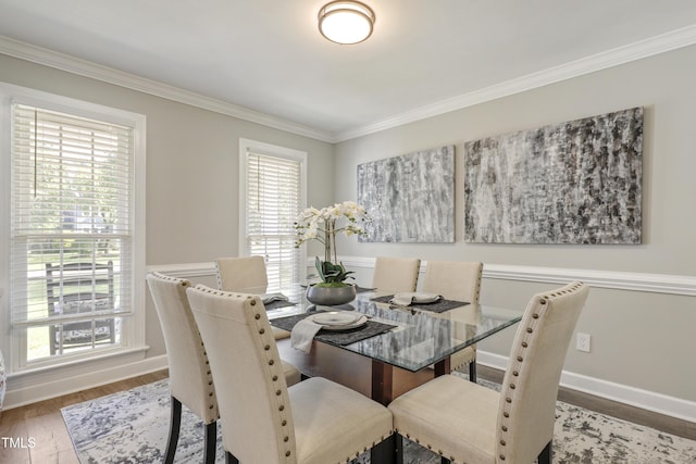 dining space featuring ornamental molding, wood finished floors, and baseboards