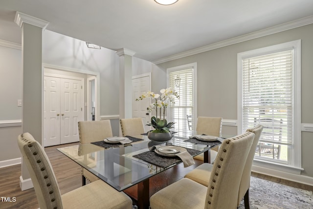 dining space with decorative columns, ornamental molding, wood finished floors, plenty of natural light, and baseboards