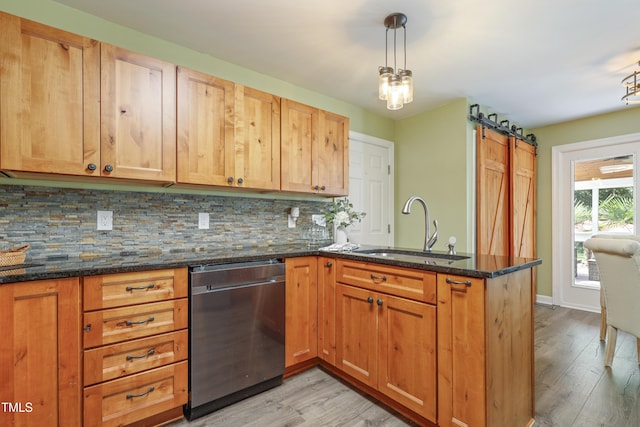kitchen featuring dishwasher, a sink, a peninsula, a barn door, and light wood-style floors