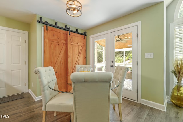dining room with wood finished floors, baseboards, a barn door, and plenty of natural light