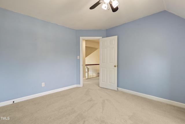 spare room featuring a ceiling fan, carpet flooring, baseboards, and vaulted ceiling