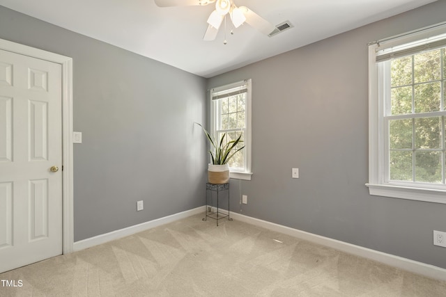 carpeted empty room with plenty of natural light, a ceiling fan, and baseboards