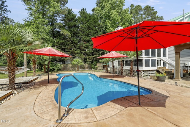 view of swimming pool featuring fence, a patio area, and a sunroom