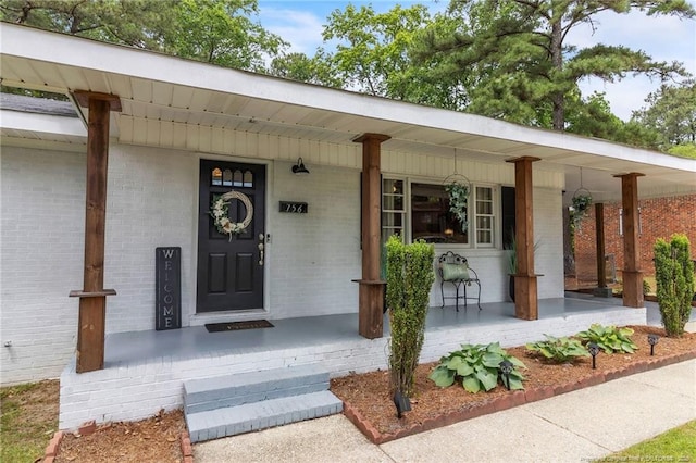 property entrance featuring covered porch and brick siding