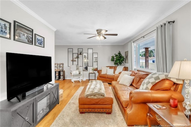 living room with light wood-type flooring, a ceiling fan, crown molding, and baseboards