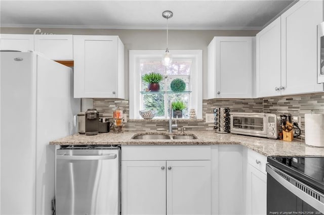 kitchen featuring stainless steel dishwasher, a sink, freestanding refrigerator, tasteful backsplash, and white cabinetry