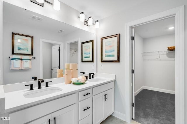 full bathroom featuring double vanity, baseboards, and a spacious closet