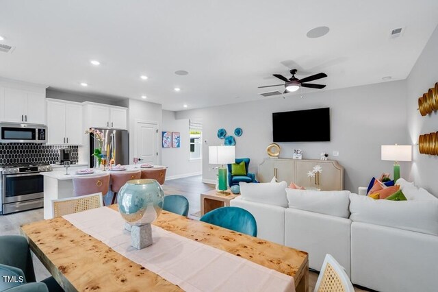 living room with light wood-style floors, recessed lighting, a ceiling fan, and baseboards