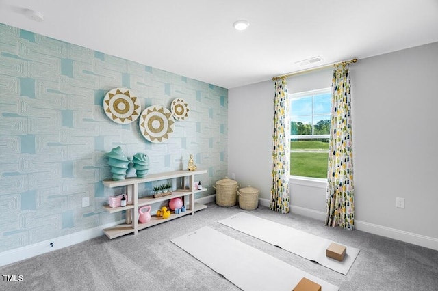 recreation room with carpet, baseboards, and an accent wall