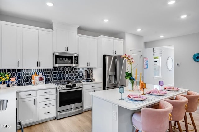 kitchen with appliances with stainless steel finishes, a kitchen island, tasteful backsplash, a kitchen bar, and recessed lighting