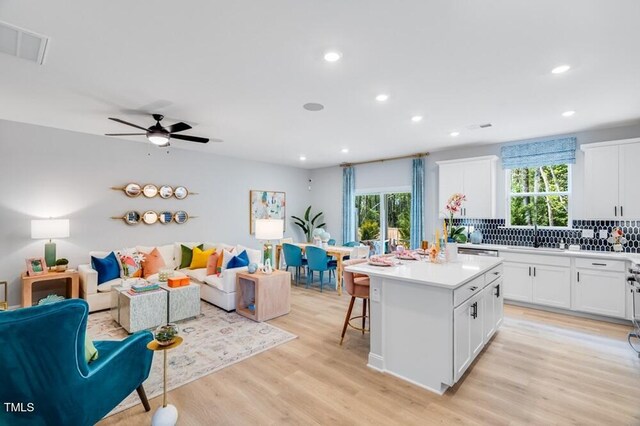 kitchen featuring open floor plan, backsplash, a kitchen island, recessed lighting, and white cabinets