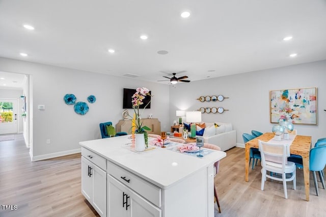kitchen featuring light wood-type flooring, white cabinets, a kitchen island, recessed lighting, and a ceiling fan