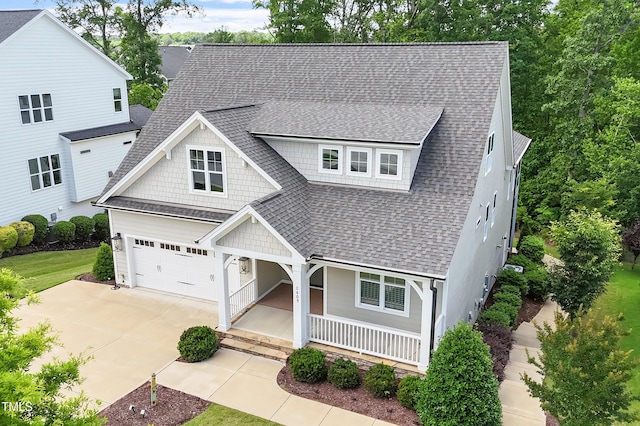 view of front of house featuring roof with shingles, covered porch, concrete driveway, and an attached garage