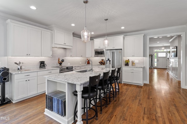 kitchen with a sink, stainless steel appliances, white cabinetry, tasteful backsplash, and a breakfast bar