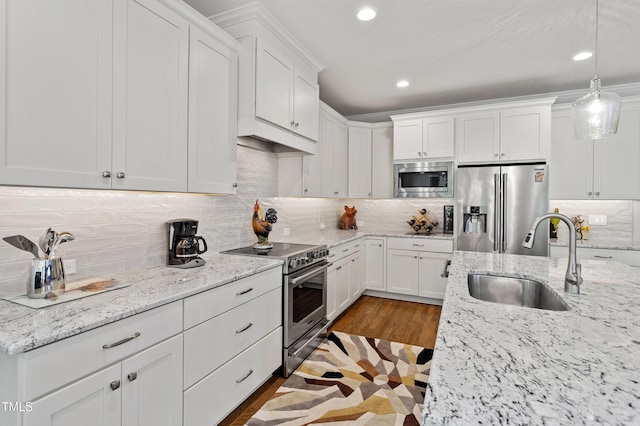 kitchen featuring stainless steel appliances, a sink, white cabinetry, recessed lighting, and decorative backsplash