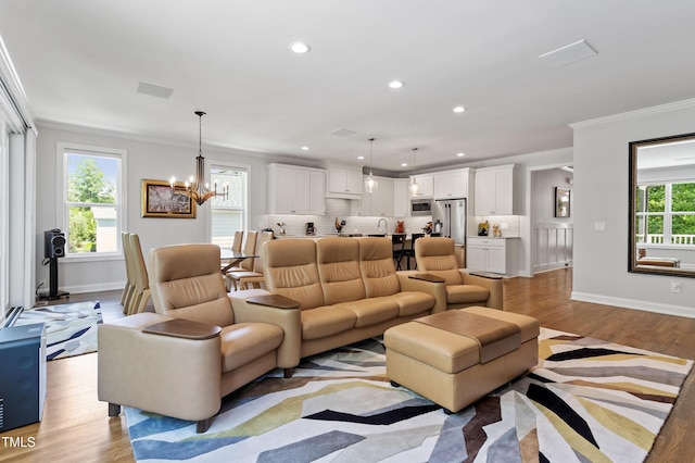 living room with crown molding, recessed lighting, a chandelier, baseboards, and light wood-style flooring