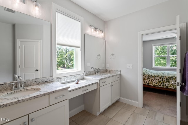 full bathroom with ensuite bathroom, tile patterned flooring, baseboards, and two vanities