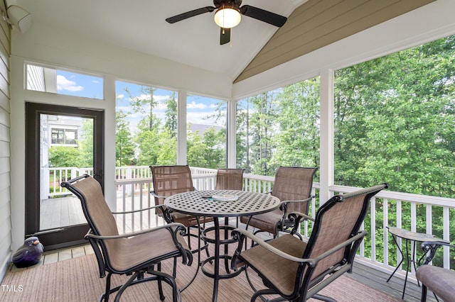 sunroom / solarium featuring lofted ceiling, a ceiling fan, and outdoor dining space