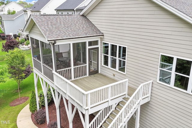 wooden deck featuring a sunroom, stairs, and a lawn