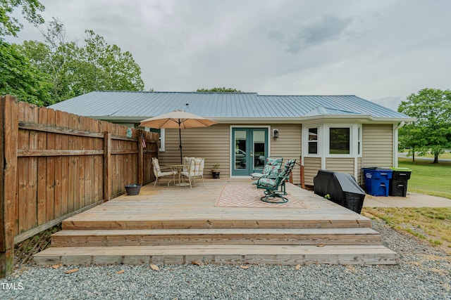 rear view of house with french doors, fence, metal roof, and a wooden deck