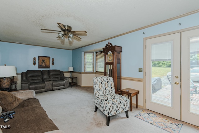 living area with ceiling fan, carpet flooring, crown molding, a textured ceiling, and baseboards