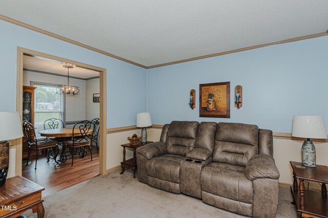 living room featuring crown molding, a chandelier, carpet floors, baseboards, and wood finished floors