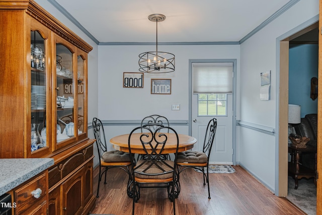 dining room with wood finished floors, a chandelier, ornamental molding, and baseboards
