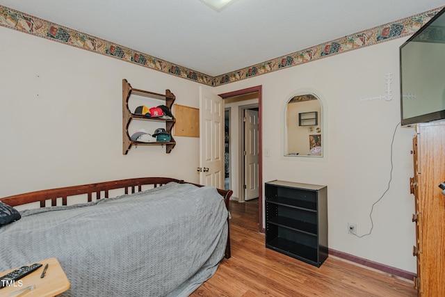 bedroom featuring light wood finished floors and baseboards