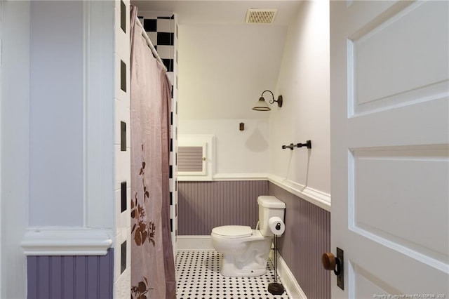 305 N Fayetteville St, Parkton, NC 28371 - bathroom with a wainscoted wall, toilet, a shower with shower curtain, and tile patterned flooring