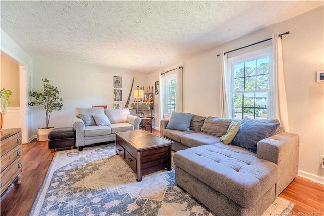 living area with wood finished floors, a textured ceiling, and baseboards