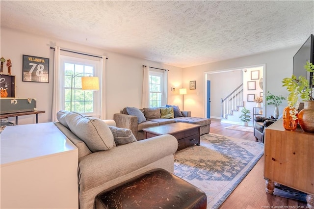 living room with wood finished floors, stairway, and a textured ceiling