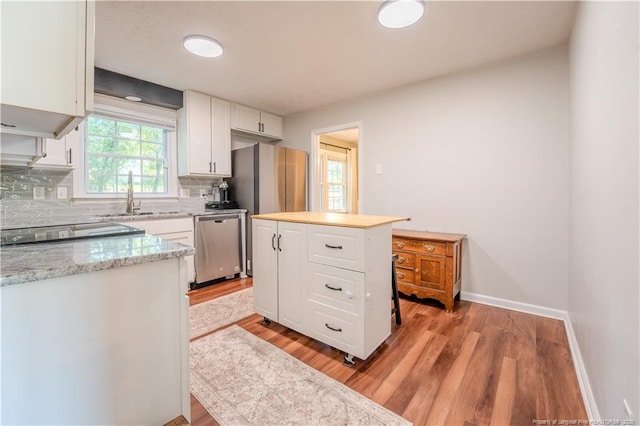 kitchen featuring stainless steel appliances, white cabinets, tasteful backsplash, light wood-style flooring, and a sink
