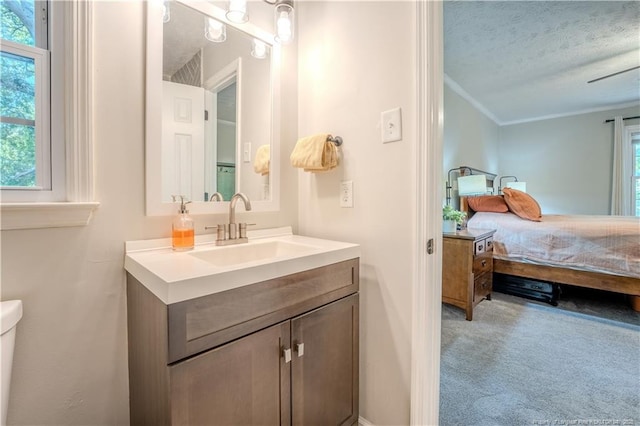 bathroom with connected bathroom, ornamental molding, a textured ceiling, vanity, and toilet