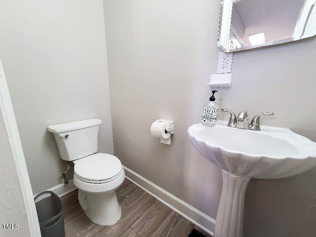 bathroom featuring toilet, wood finished floors, and baseboards