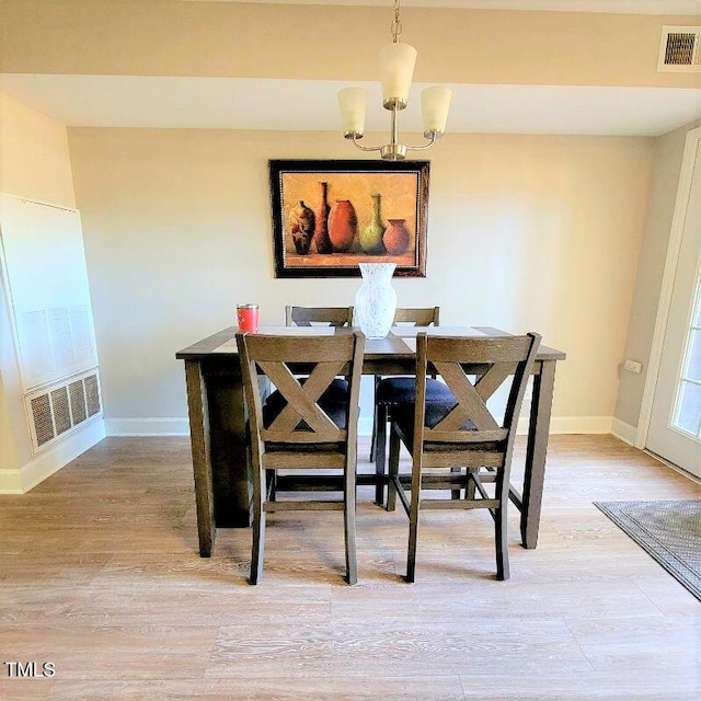 dining area with baseboards, a chandelier, and light wood finished floors