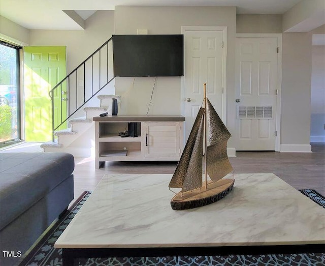 living area featuring stairs, wood finished floors, and baseboards