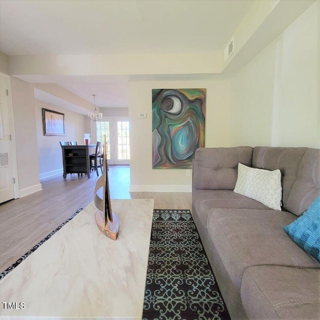 living area featuring baseboards, wood finished floors, and a chandelier