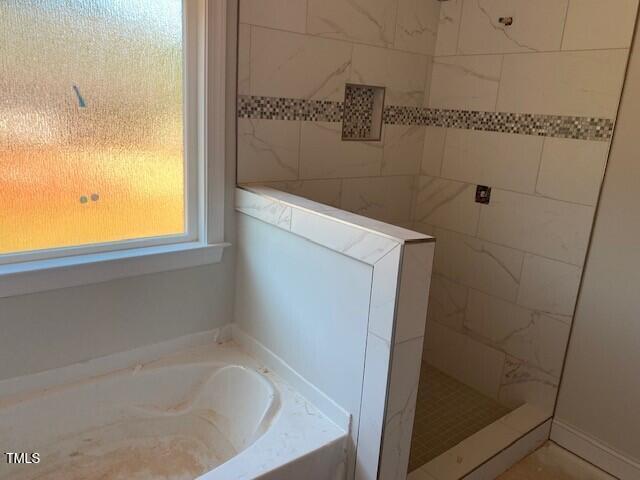 bathroom featuring walk in shower and a bath