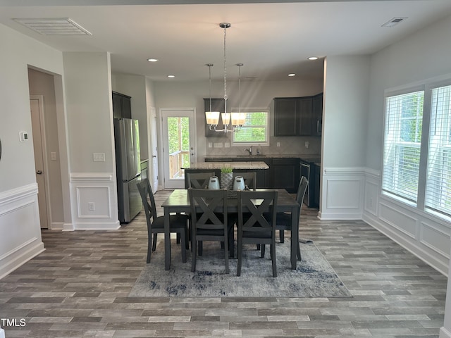 dining area featuring a chandelier, wood finished floors, a decorative wall, recessed lighting, and a wainscoted wall