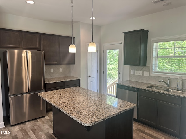 kitchen featuring stainless steel appliances, a sink, light stone countertops, dark wood finished floors, and decorative backsplash