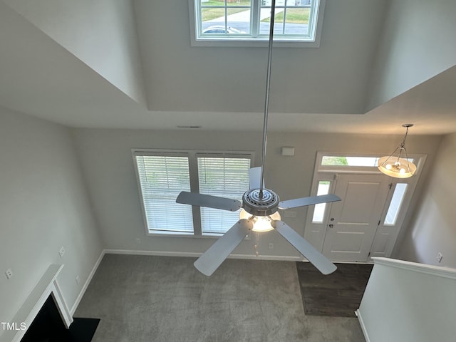 foyer with a high ceiling, baseboards, carpet, and a ceiling fan