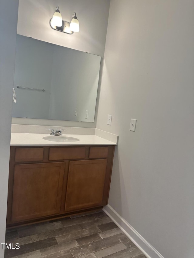 bathroom with wood finished floors, vanity, and baseboards