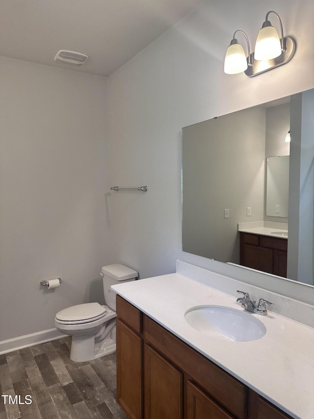 bathroom featuring toilet, wood finished floors, and vanity