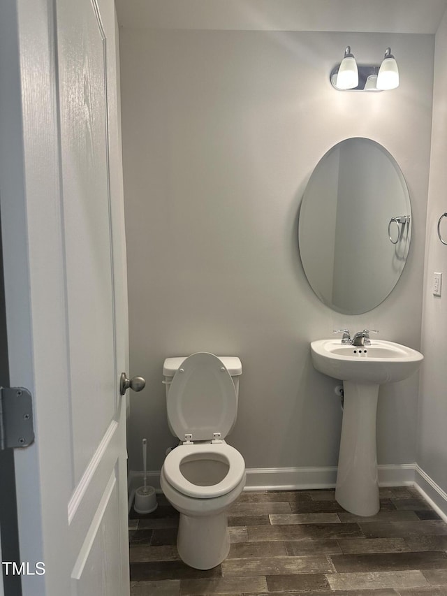 bathroom featuring wood finish floors, baseboards, and toilet