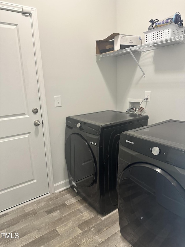 washroom with independent washer and dryer, wood finished floors, and baseboards