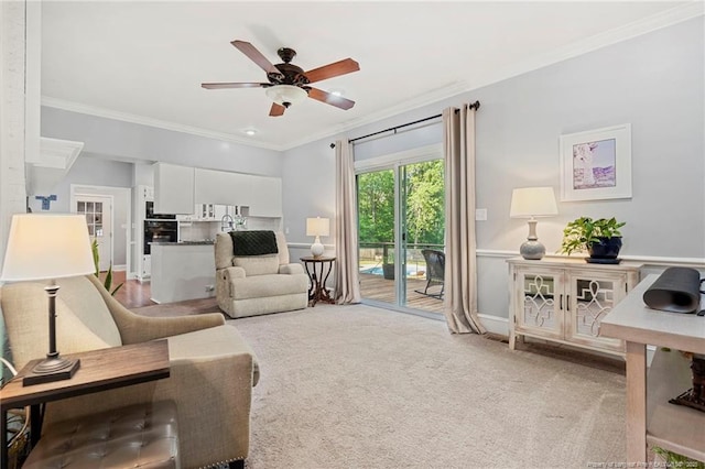 living area with ceiling fan, crown molding, light carpet, and baseboards
