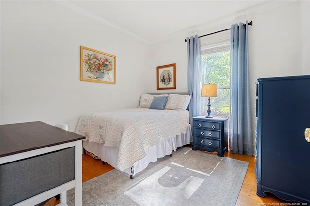bedroom with ornamental molding and wood finished floors