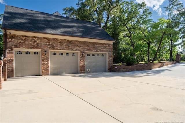 view of property exterior featuring driveway, brick siding, roof with shingles, and an attached garage