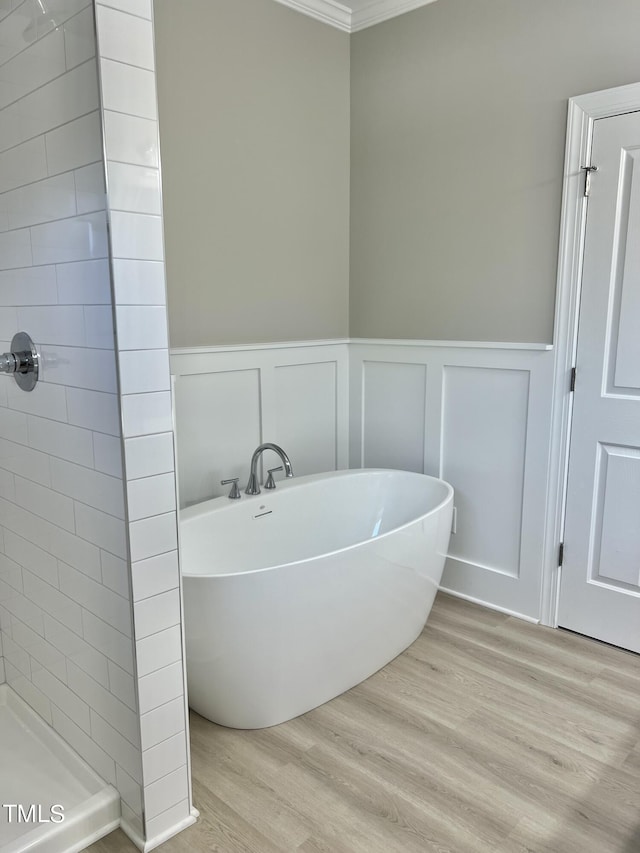 4016 Berman Edge Rd, Holly Springs, NC 27540 - bathroom with wood finished floors, ornamental molding, a freestanding tub, tiled shower, and a decorative wall